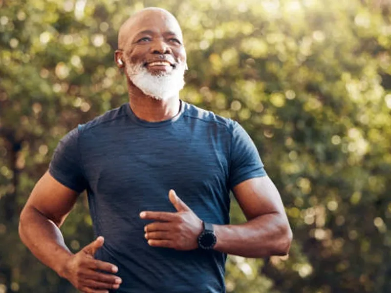 A smiling older man jogging outdoors